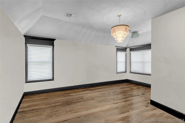 spare room with light hardwood / wood-style floors, vaulted ceiling, and a chandelier