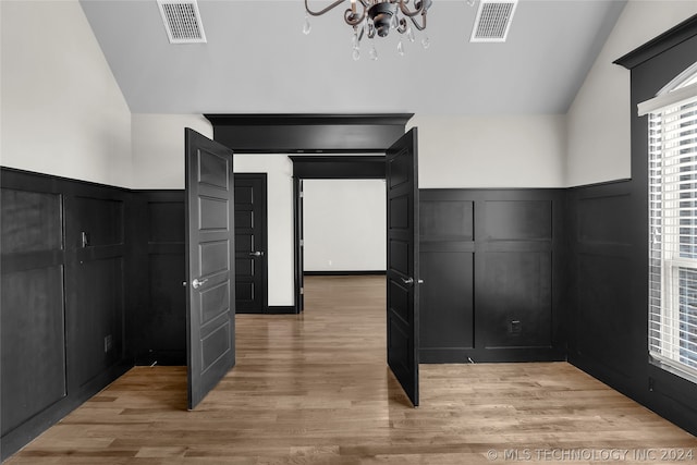 interior space featuring vaulted ceiling, an inviting chandelier, and light wood-type flooring