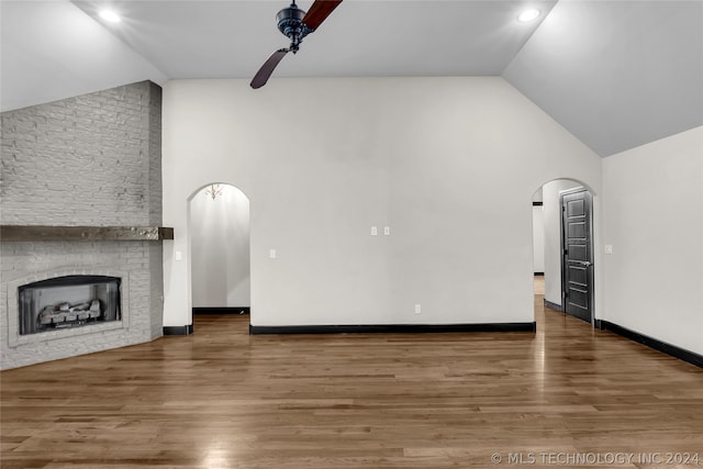 unfurnished living room featuring hardwood / wood-style flooring, high vaulted ceiling, a fireplace, and ceiling fan