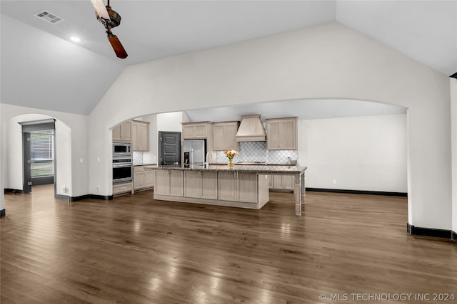 kitchen with ceiling fan, dark wood-type flooring, premium range hood, and an island with sink