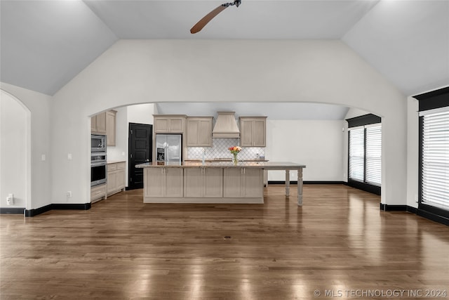 kitchen with hardwood / wood-style flooring, stainless steel appliances, premium range hood, and tasteful backsplash