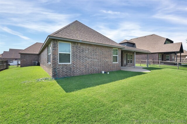 rear view of house with central AC, a yard, and a patio area