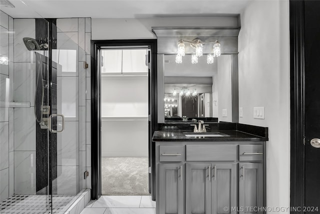 bathroom featuring tile patterned flooring, a shower with shower door, and vanity