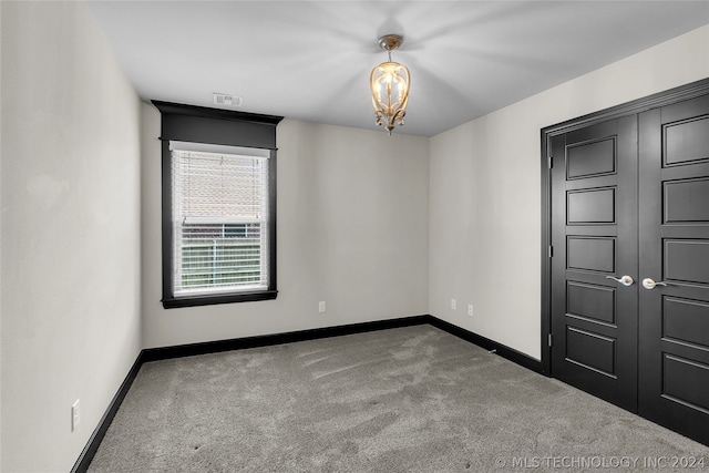 unfurnished bedroom featuring a chandelier and carpet flooring