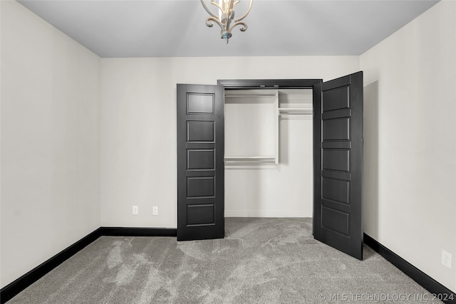 unfurnished bedroom with an inviting chandelier, carpet, and a closet