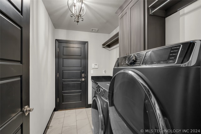 clothes washing area featuring light tile patterned flooring, cabinets, and washer and dryer