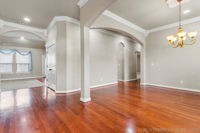 empty room with an inviting chandelier, dark wood-type flooring, and ornamental molding