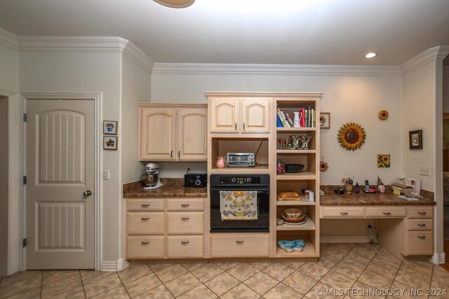 kitchen with ornamental molding, light tile patterned floors, oven, and light brown cabinetry