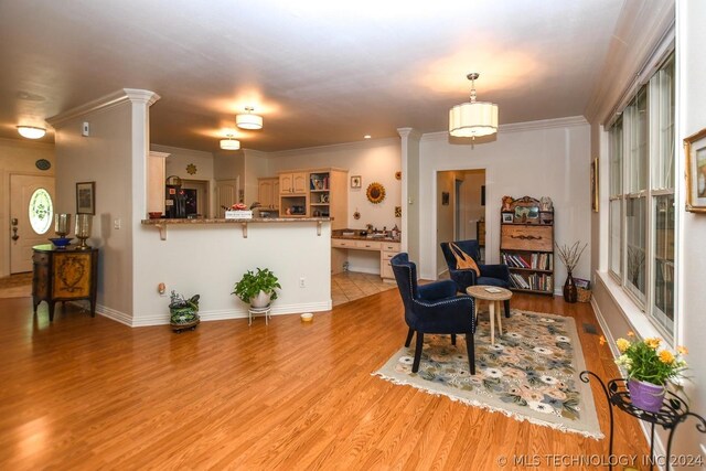 living room with decorative columns, crown molding, and light wood-type flooring