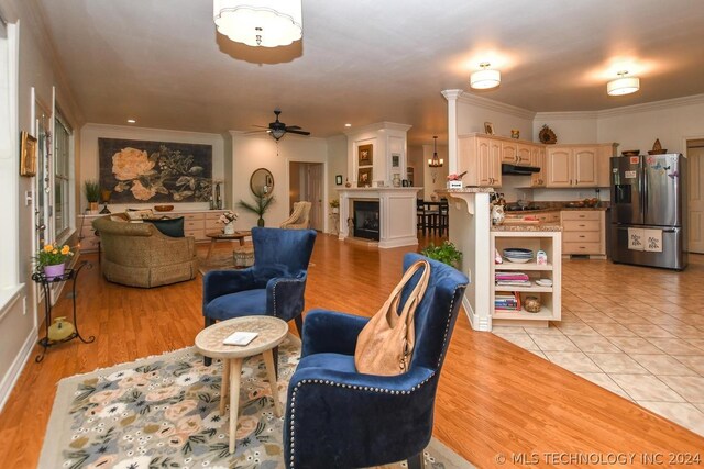 living room featuring crown molding, light hardwood / wood-style floors, and ceiling fan