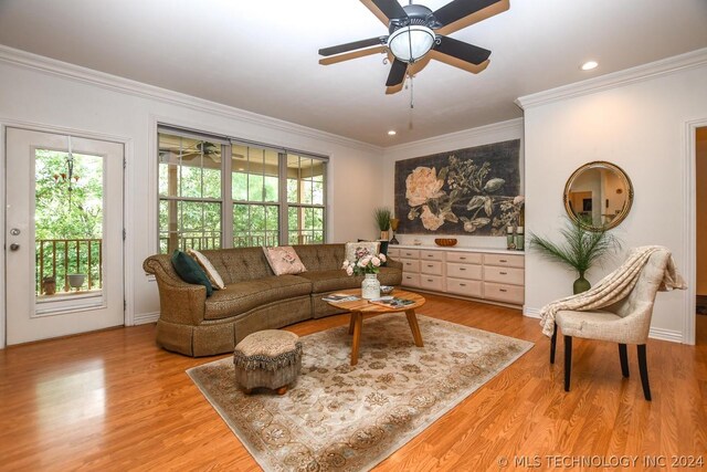 living room with ornamental molding, ceiling fan, and light wood-type flooring