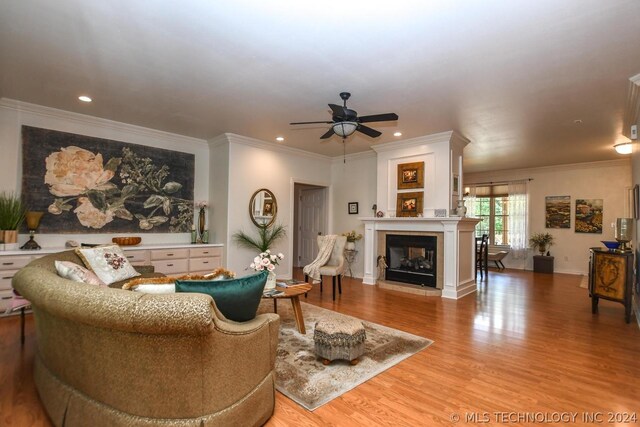 living room featuring wood-type flooring, ornamental molding, and ceiling fan