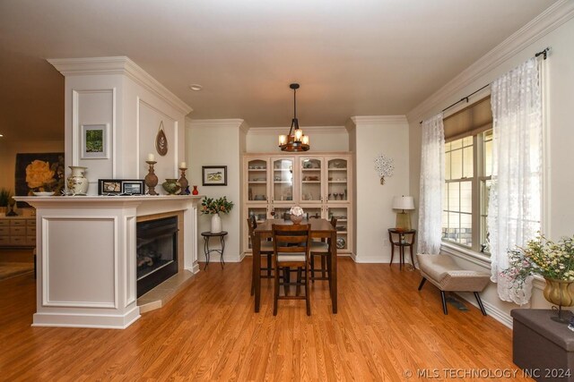 dining space featuring light hardwood / wood-style flooring, ornamental molding, and a chandelier