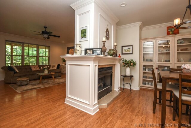 living room with ornamental molding, a fireplace, ceiling fan with notable chandelier, and light hardwood / wood-style flooring