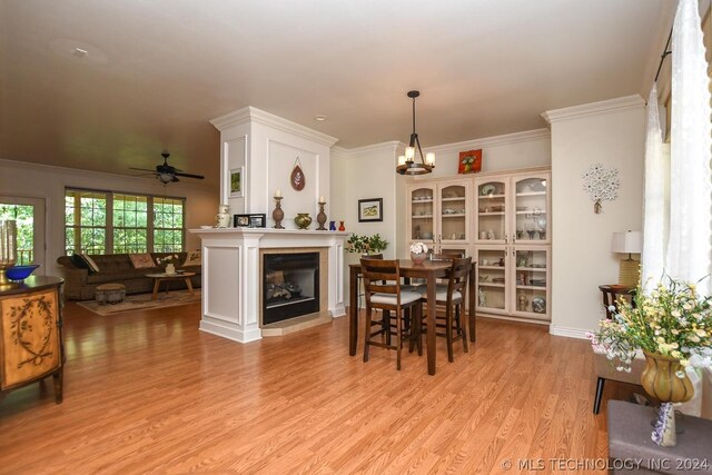 dining room featuring crown molding, ceiling fan with notable chandelier, and light wood-type flooring