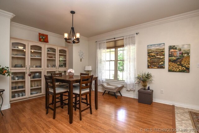 dining space with ornamental molding, hardwood / wood-style floors, and a chandelier