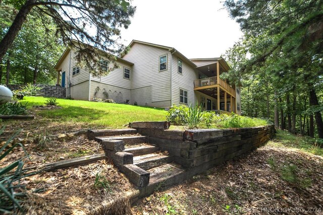 rear view of house featuring a balcony and a lawn