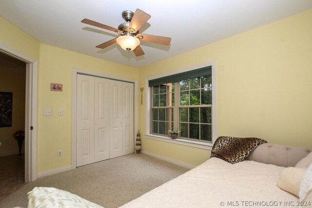 carpeted bedroom with ceiling fan and a closet