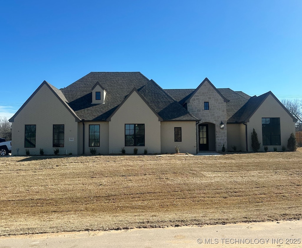 french country inspired facade featuring a front lawn