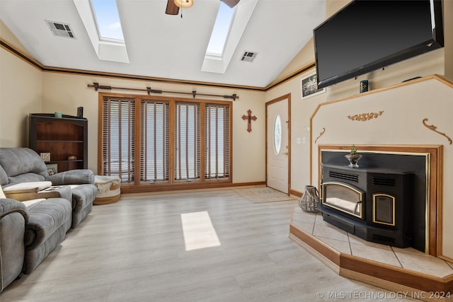 living room featuring lofted ceiling, ceiling fan, a wood stove, and light hardwood / wood-style flooring