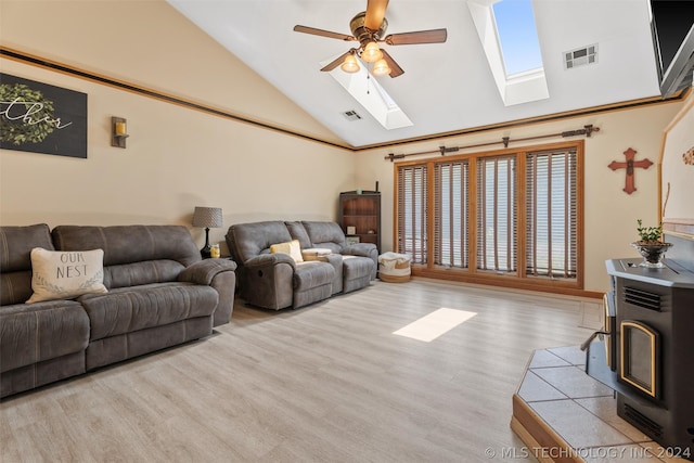 living room with a wood stove, ceiling fan, a skylight, high vaulted ceiling, and light hardwood / wood-style floors