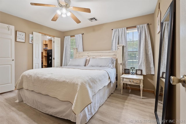 bedroom featuring ceiling fan, light hardwood / wood-style floors, and multiple windows