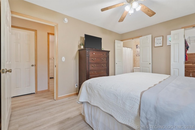 bedroom with a closet, ceiling fan, light hardwood / wood-style flooring, and a walk in closet