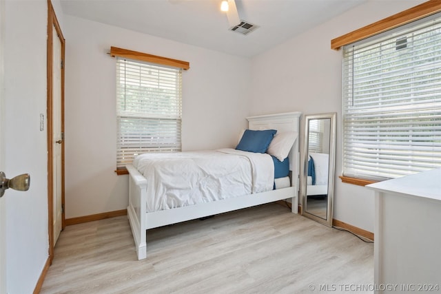 bedroom with light wood-type flooring, a closet, multiple windows, and ceiling fan