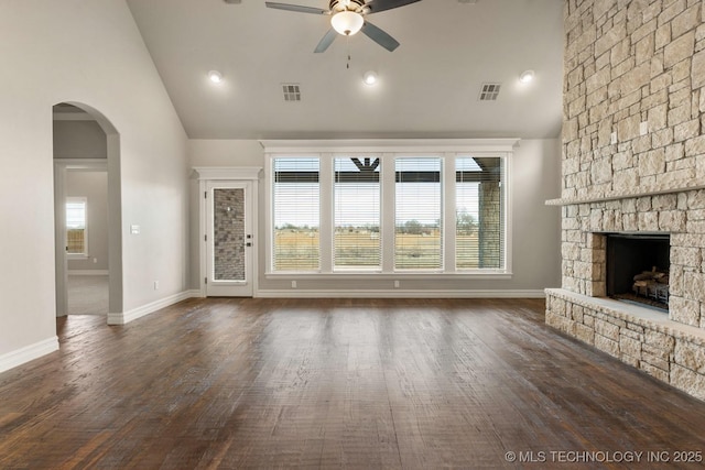 unfurnished living room featuring ceiling fan, visible vents, arched walkways, and a stone fireplace