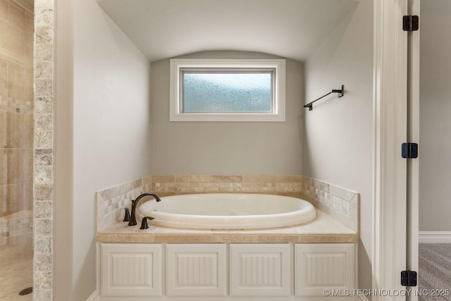 bathroom featuring vaulted ceiling, a tile shower, and a bath