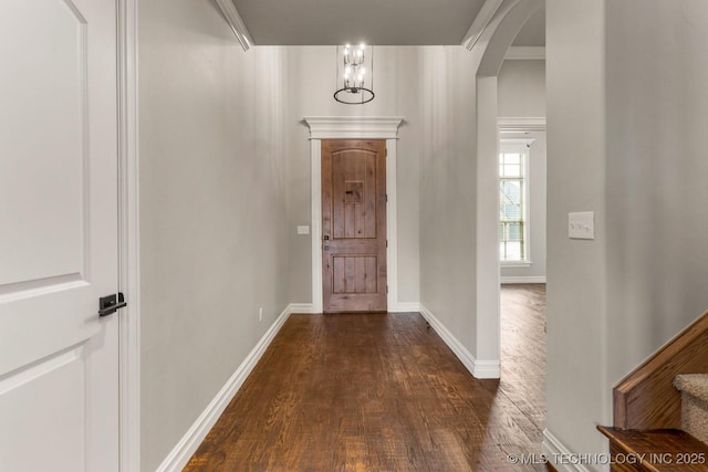 entryway featuring baseboards, stairs, arched walkways, and dark wood-type flooring