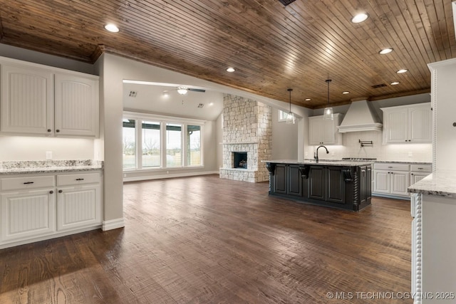 kitchen featuring dark wood finished floors, crown molding, custom exhaust hood, a fireplace, and white cabinetry