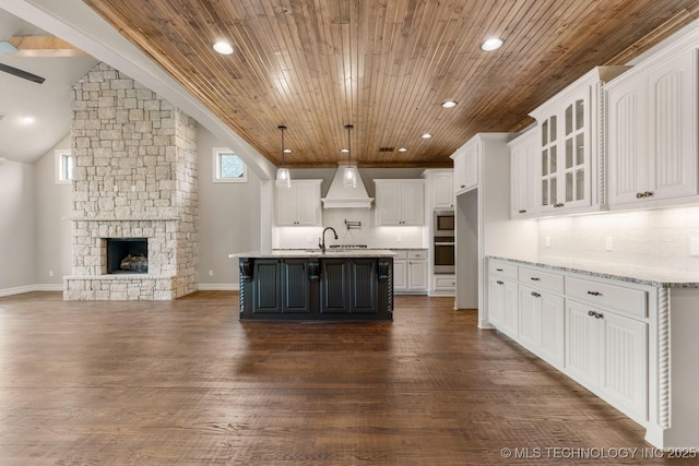 kitchen with dark wood-style floors, a fireplace, custom range hood, open floor plan, and white cabinetry