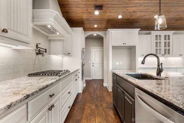 kitchen with visible vents, arched walkways, stainless steel appliances, premium range hood, and a sink