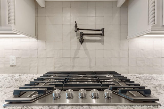 interior details featuring light stone counters, stainless steel gas cooktop, and decorative backsplash