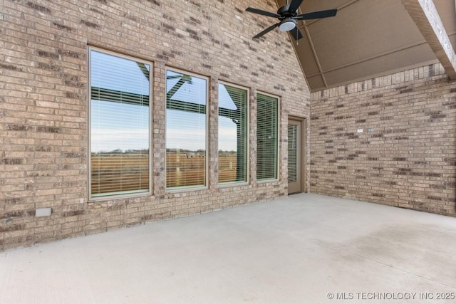 exterior space featuring concrete flooring, brick wall, and a ceiling fan