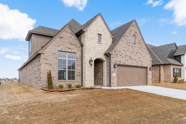 french provincial home with roof with shingles, concrete driveway, and brick siding