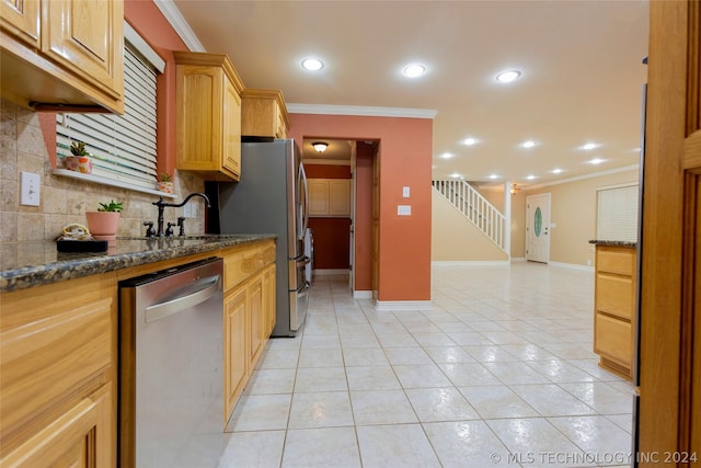 kitchen with appliances with stainless steel finishes, dark stone counters, light tile patterned floors, and crown molding