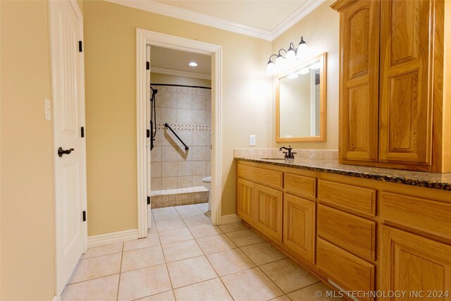 bathroom with tile patterned floors, crown molding, vanity, and toilet