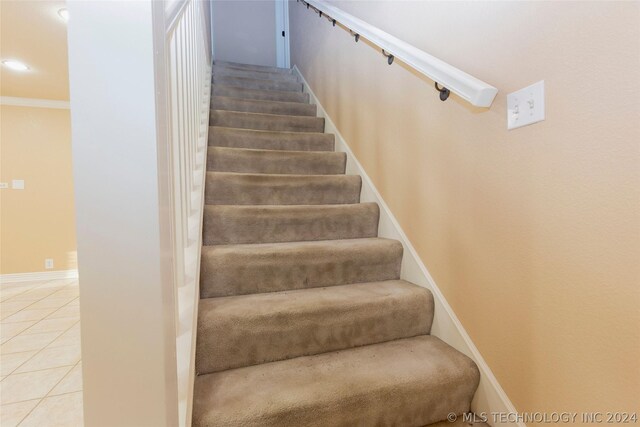 staircase with tile patterned flooring and crown molding