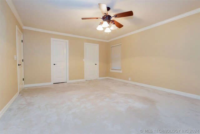 unfurnished bedroom featuring light colored carpet, ceiling fan, and crown molding