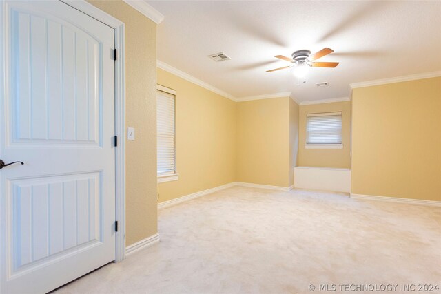 empty room featuring ceiling fan, light colored carpet, and ornamental molding