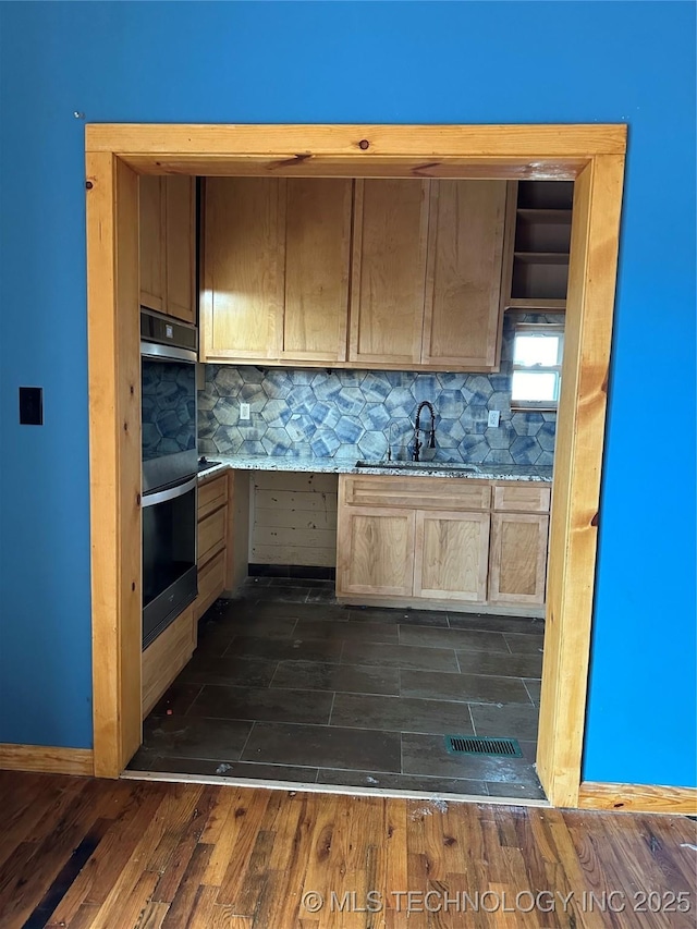 kitchen featuring sink, black double oven, dark wood-type flooring, and backsplash