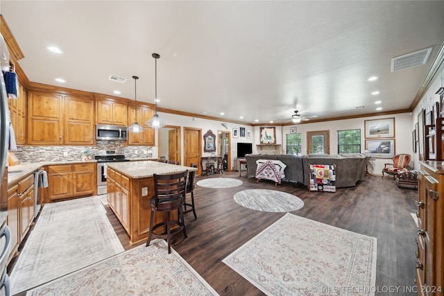 kitchen with ceiling fan, stainless steel appliances, crown molding, a kitchen island, and dark wood-type flooring