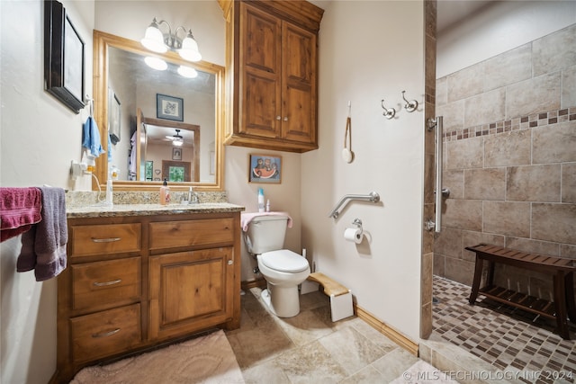 bathroom featuring vanity, tiled shower, toilet, and tile patterned floors