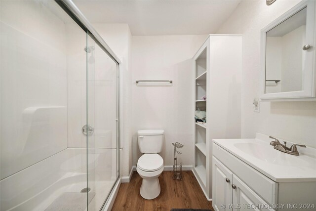 bathroom featuring a shower with door, vanity, hardwood / wood-style flooring, and toilet