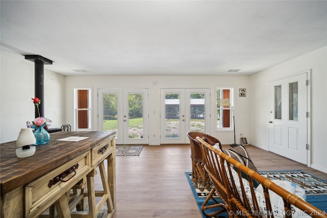 dining space featuring a wood stove, wood-type flooring, and french doors