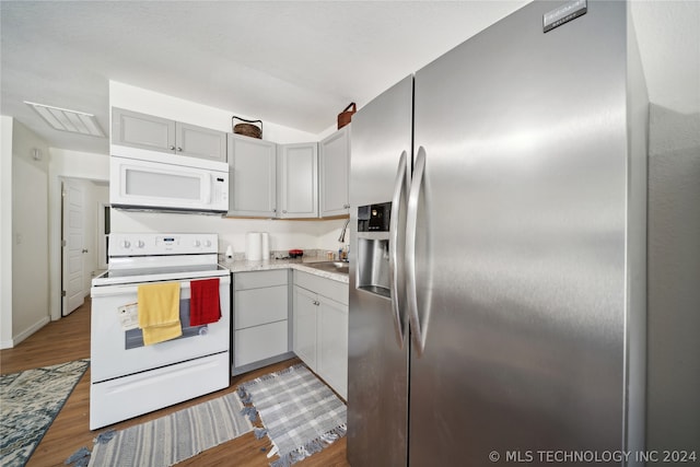 kitchen with light hardwood / wood-style flooring, white appliances, and gray cabinetry