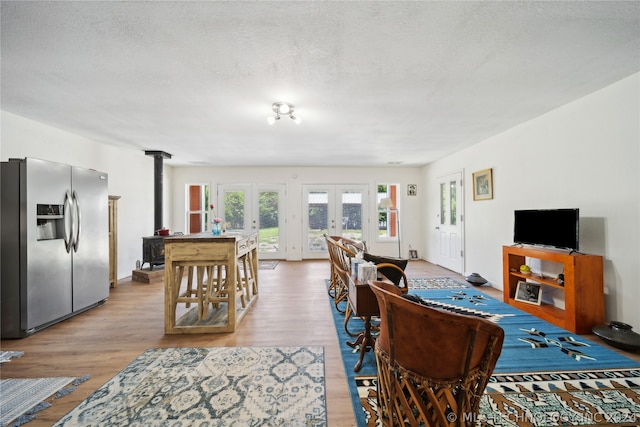 living room featuring a textured ceiling, french doors, wood-type flooring, and a wood stove