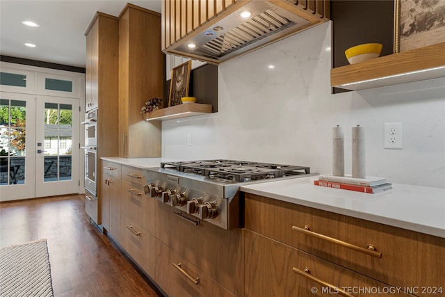 kitchen with french doors, premium range hood, light stone counters, dark hardwood / wood-style flooring, and appliances with stainless steel finishes